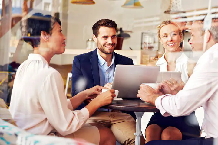 group of adults sitting in a coffee shop discussing clear goals to set for their website