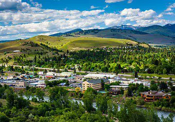 view of green and lush downtown Missoula, Montana from the top of a hill during the summertime
