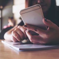 woman holding an ipad looking at analytics information and graphs surrounded by two other people looking at the data